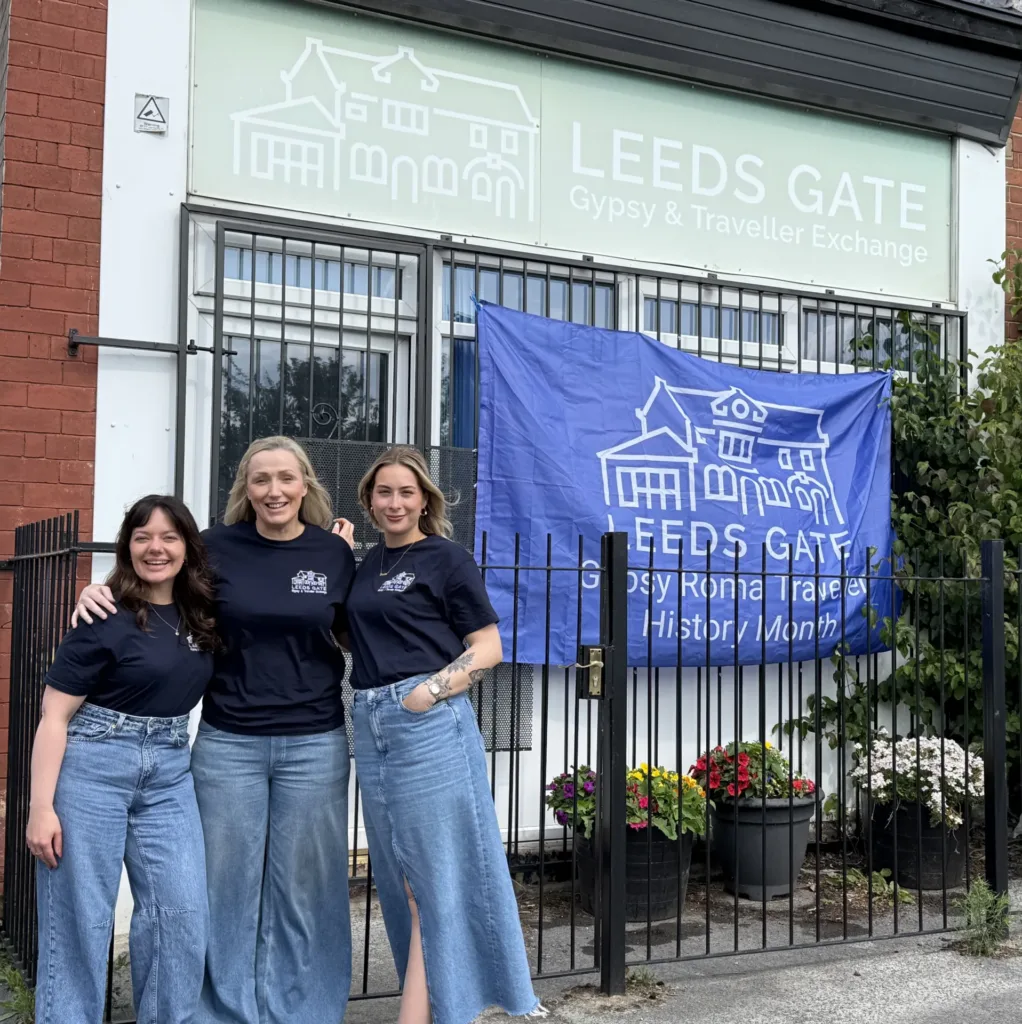 Three women stand outside the Leeds GATE office building with arms around each other. The three women are our mental health support team.